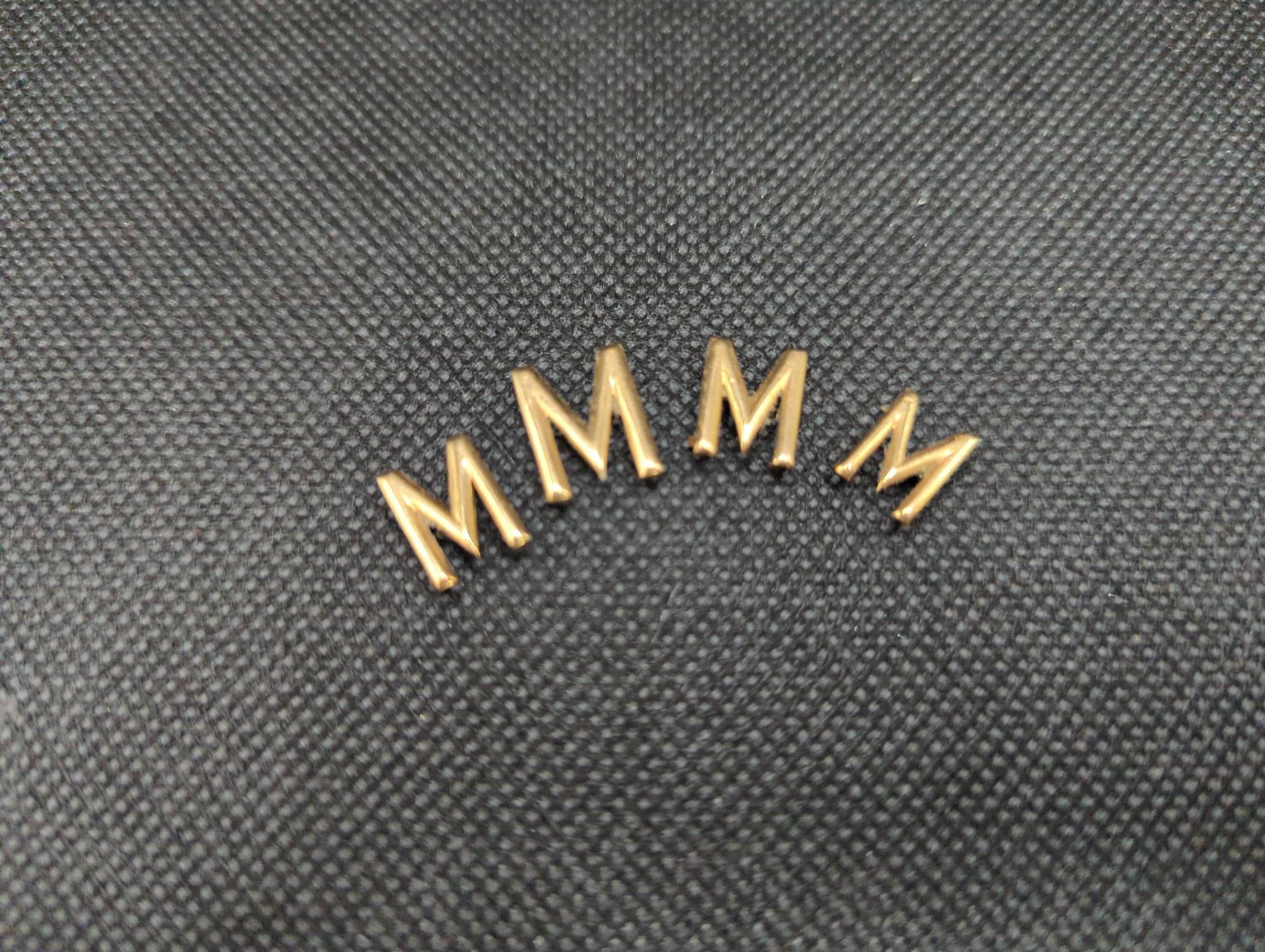 Four yellow metal letter 'M' appliques, gross weight 2.4 grams.